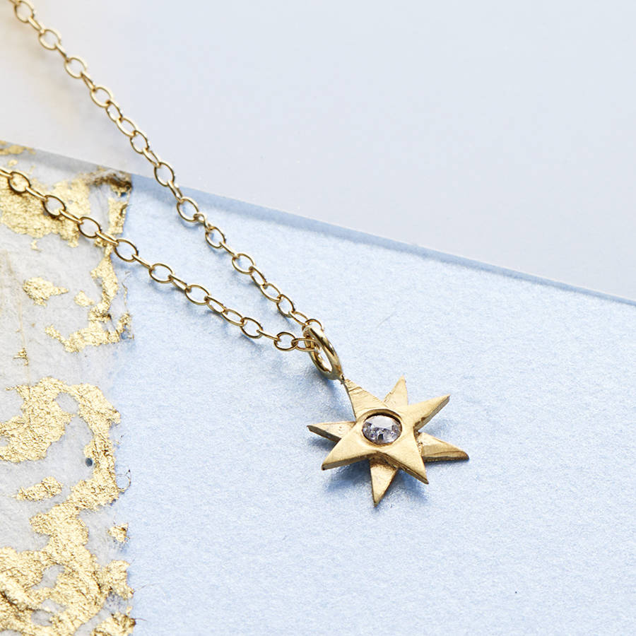 gold tiny star necklace set with a white sapphire 